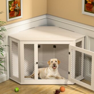 Dog laying in a corner wooden crate with open door, toys outside.