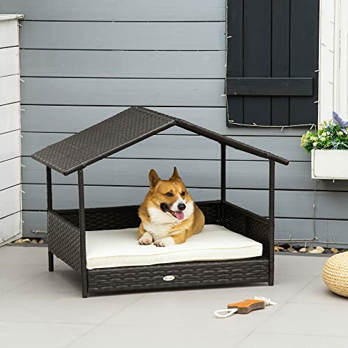 Dog resting in a wicker outdoor dog house with a cushion.