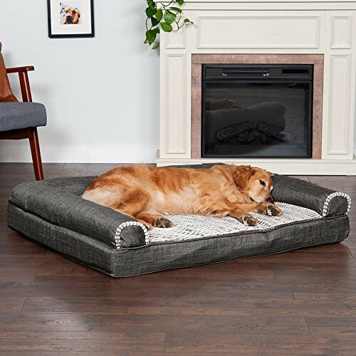 Dog sleeping on a large pet bed in front of a fireplace.